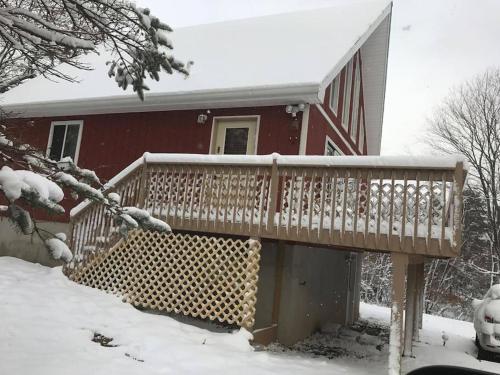 a house with a wooden deck in the snow at Beautiful Chalet with Hot Tub & Sauna in Poconos in Long Pond