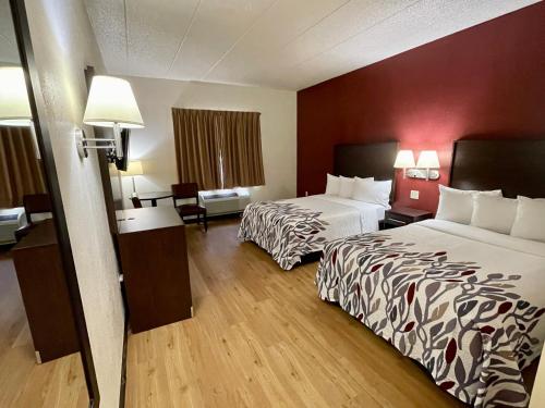 a hotel room with two beds and a table and chairs at Red Roof Inn Sandusky - Milan in Milan