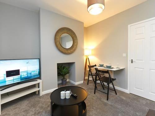 a living room with a flat screen tv and a table at Flat 1 Castle Street Serviced Apartments in Telford