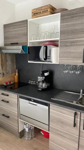 une cuisine avec un comptoir noir avec un micro-ondes dans l'établissement APPARTEMENT T2 GRUISSAN PLAGE DANS RÉSIDENCE CALME, à Gruissan