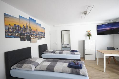 a bedroom with two beds and a table and a desk at Schaefer Apartments - Residence Green Garden in Offenbach