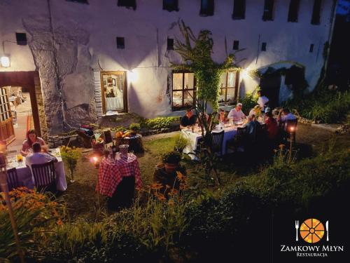 a group of people sitting at tables in a garden at night at Hotel Zamkowy Młyn in Krapkowice
