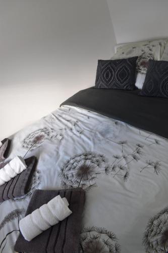 a bed with a black and white comforter and pillows at Apartma VRBA Dobrna in Dobrna