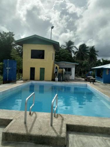 a large blue swimming pool with a house in the background at Hideaway Resort Victoria secret hideaway resort in Maraat