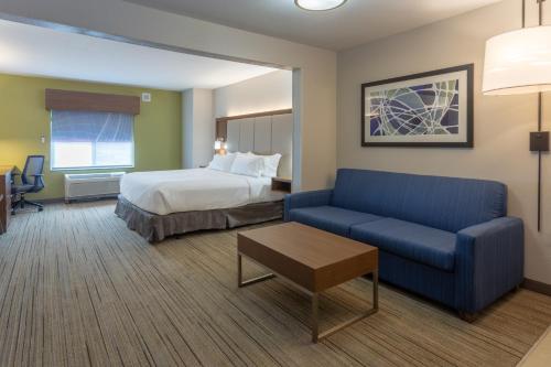 Habitación de hotel con cama y sofá azul en Holiday Inn Express & Suites Milwaukee NW - Park Place, an IHG Hotel en Milwaukee