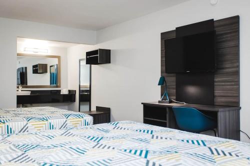a hotel room with two beds and a desk and a tv at Studio 6 Houston TX Medical Center NRG Stadium in Houston