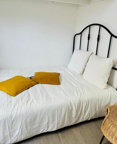 a bed with white sheets and yellow pillows at Magnifique studio in Bagnolet