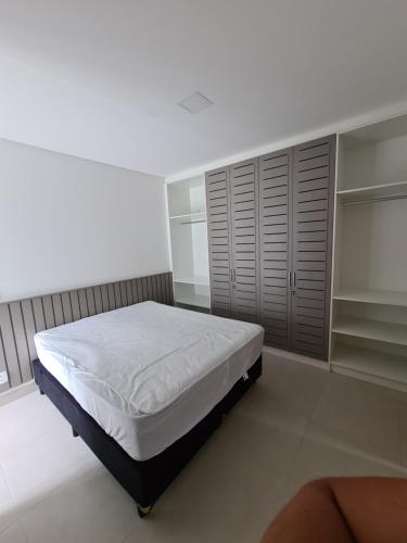 a white bedroom with a bed and a closet at Apartamento Ubatuba Reserva DNA in Ubatuba