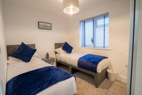a bedroom with two beds and a window and a tub at Mill Road Ground Floor Apartment in Crawley