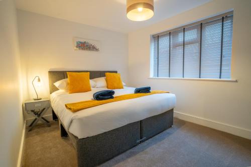 a bedroom with a bed with orange pillows and a window at Mill Road Ground Floor Apartment in Crawley