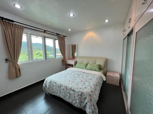 a bedroom with a bed and two windows at MAGICAL HOMESTAY CAMERON HIGHLANDS in Cameron Highlands