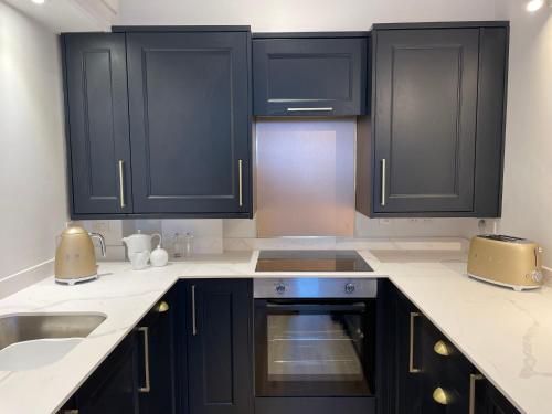 a kitchen with black cabinets and a sink at Beachside Apartment in Carbis Bay