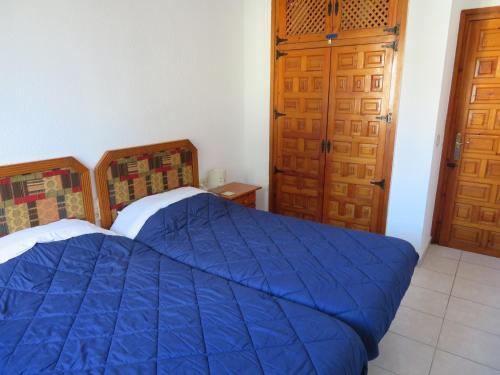 1 dormitorio con cama azul y puertas de madera en Apartment Gloria, en Denia