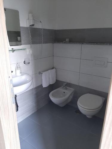 a white bathroom with a toilet and a sink at Hotel Conca d'Oro in Stalettì