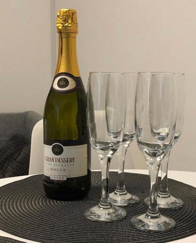 a bottle of champagne and four wine glasses on a table at Apartman Bloom in Osijek