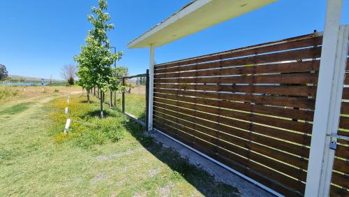 a wooden fence next to a field with a tree at Casa Lago Rapel, Las Cabras in Las Balsas