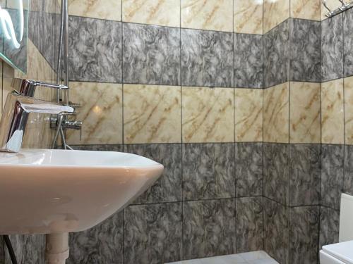 a bathroom with a sink and a tiled wall at LA ROCHELLE HOTEL in Yaoundé