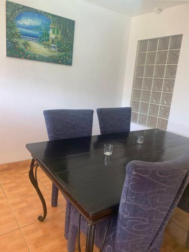a black table with chairs and a painting on the wall at Cool Running Apartments in Saint Georgeʼs