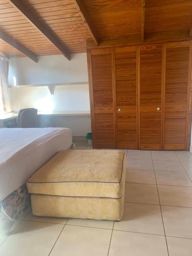 a bedroom with a bed and wooden cabinets and a stool at Cool Running Apartments in Saint Georgeʼs