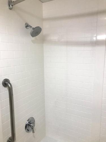 a bathroom with a shower with a white tile wall at Comfort Suites Outlet Center in Asheville