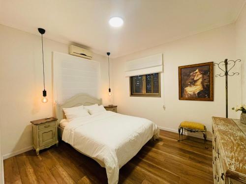 a bedroom with a bed and a painting on the wall at Orlinka in Tirat Yehuda