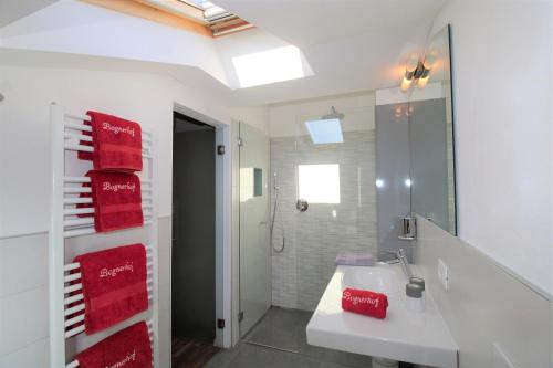 a bathroom with a sink and a shower with red towels at Bognerhof in Rifiano