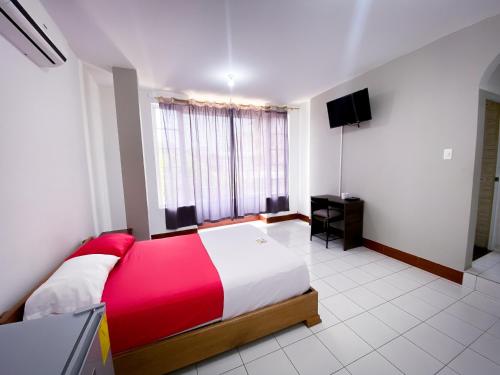 a bedroom with a red and white bed and a television at Hostal Casa Blanca in El Coca