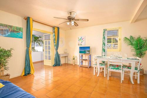 a living room with a table and chairs and a ceiling fan at La villa du rocher du Gaïac avec Spa in Le Diamant