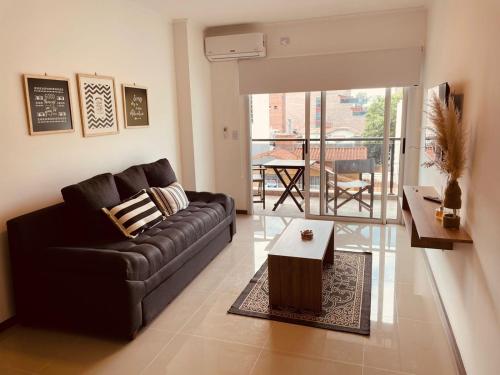 a living room with a black couch and a table at Departamento frente al lago en Villa Carlos Paz in Villa Carlos Paz