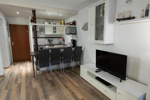 ein Wohnzimmer mit einem Flachbild-TV und eine Küche in der Unterkunft Ferienpark Steinhude - Neptun 115 in Wunstorf