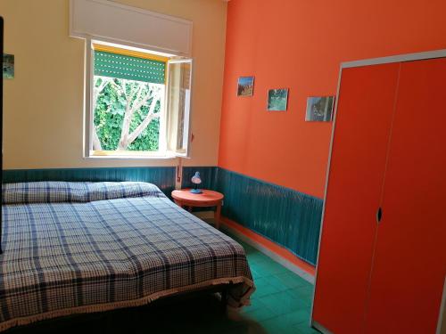 1 dormitorio con paredes de color naranja, 1 cama y ventana en Villa Arya Casa Vacanza, en Riposto