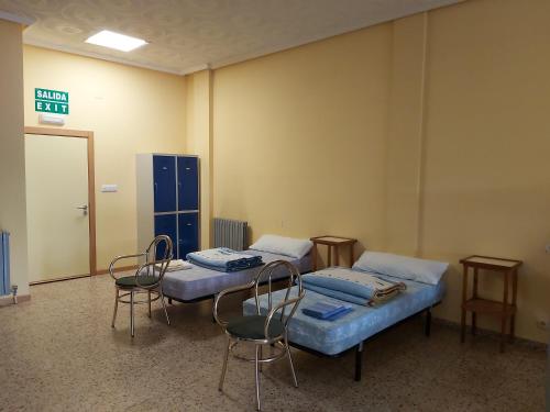 una habitación hospitalaria con 2 camas y sillas y un letrero de salida en Casa Cerviño, en Requejo