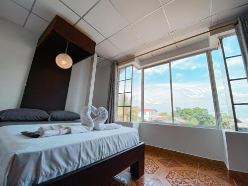 a bedroom with a bed and a large window at Hostal Casa Blanca in El Coca