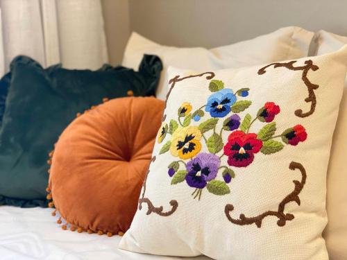 a bed with pillows and a pillow with flowers on it at Apto temático Pintura e Porcelana Centro Pomerode in Pomerode