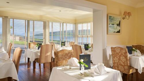 ディングルにあるHeatons Guesthouseの白いテーブルと椅子、窓のあるレストラン