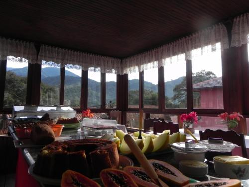una mesa con comida en ella con montañas en el fondo en Pousada Solar das Flores en Visconde De Maua