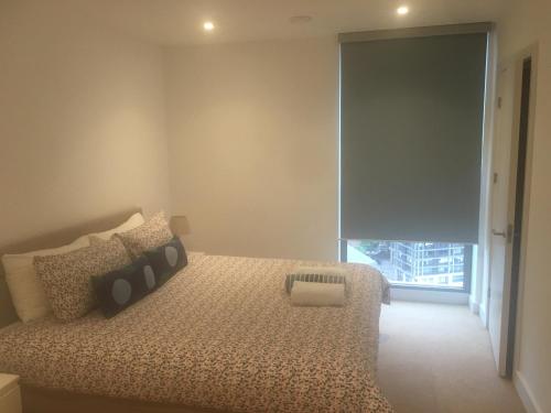 - une chambre avec un lit et une grande fenêtre dans l'établissement Luxurious serviced apartment in Croydon, à Croydon