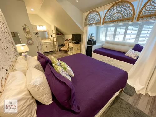 a bedroom with a bed with purple sheets and pillows at Bama Bed and Breakfast - Wisteria Suite in Tuscaloosa