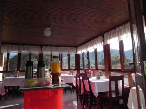 a dining room with tables and chairs and windows at Pousada Solar das Flores Maringá RJ Visconde de Mauá in Visconde De Maua