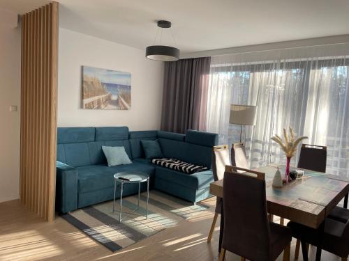a living room with a blue couch and a table at Apartamenty Marco Polo in Dziwnówek