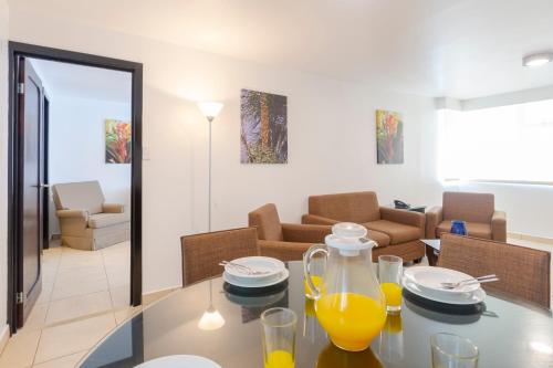 a living room with a glass table with orange juice on it at Hotel Residence Inn Suites Cristina in San José