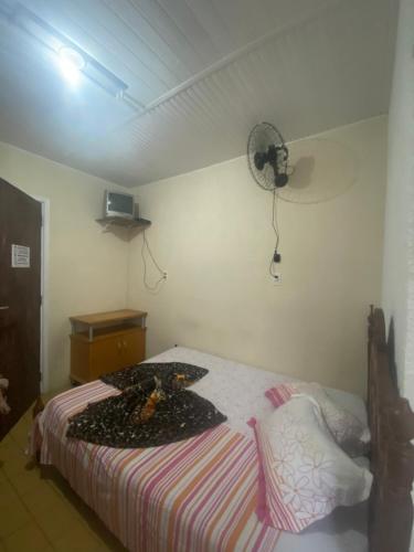 a bedroom with a bed and a fan on the wall at Pousada J.C. Cazeri in Santos