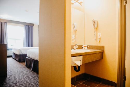 baño con lavabo, cama y espejo en Super 8 by Wyndham Revelstoke BC en Revelstoke