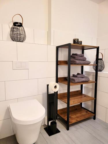 a bathroom with a toilet and a shelf with towels at Das Stader Quartier in Stade