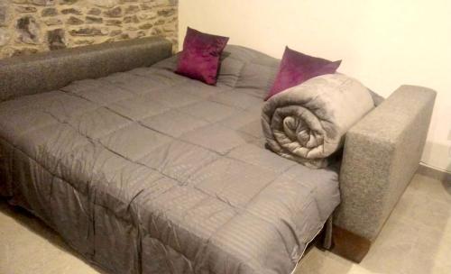 a gray bed with pillows on top of it at Atrani in Santeagueda