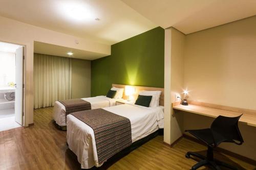 a hotel room with a bed and a desk at Hotel Vila Rica Campinas in Campinas