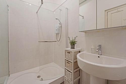 y baño blanco con lavabo y ducha. en Cozy with Character Logie Green Central Main Door Flat, en Edimburgo