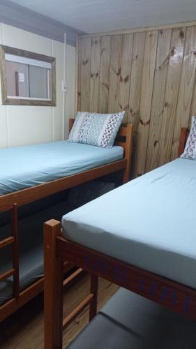 two beds in a room with wooden walls at Trip Adventure Hostel in Porto Belo