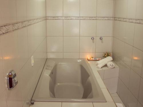 a white bath tub in a white tiled bathroom at Hotel Alpenrose in Treze Tílias