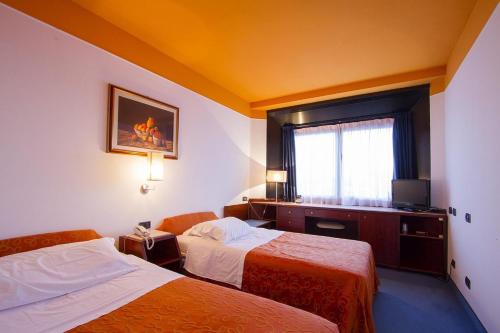 a hotel room with two beds and a window at Hotel sirena in Cesenatico